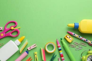 Photo of Glue in bottles and other stationery on green background, flat lay. Space for text