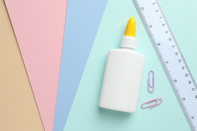 Photo of Glue in bottle, ruler and paper clips on color paper, flat lay. Space for text