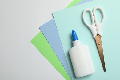 Photo of Glue, scissors and color paper on white background, flat lay