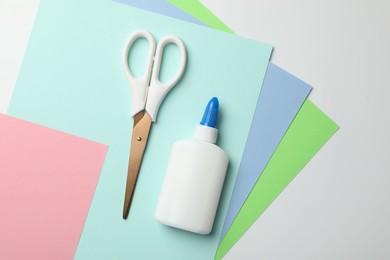 Photo of Glue, scissors and color paper on white background, flat lay