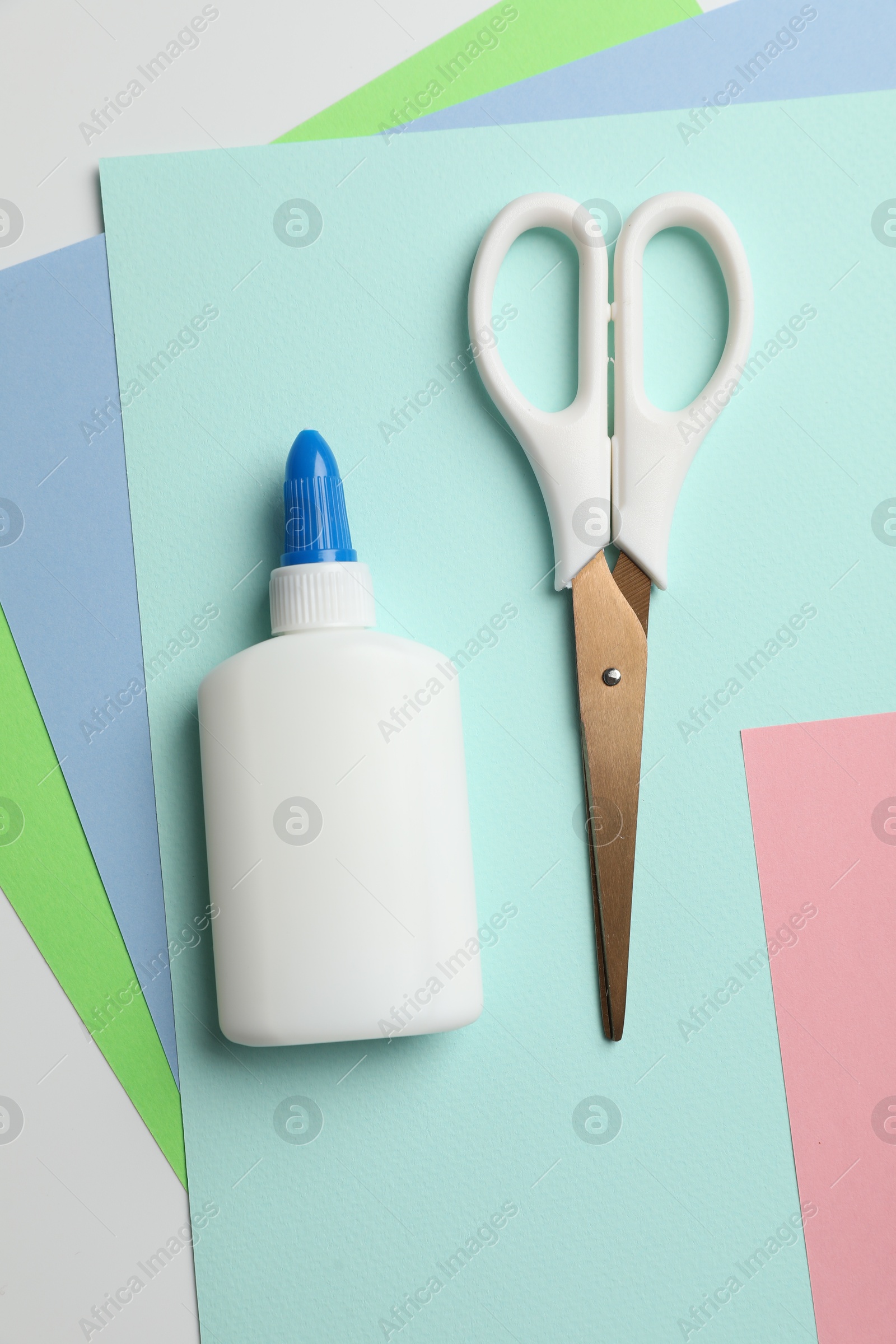 Photo of Glue, scissors and color paper on white background, flat lay