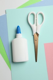 Photo of Glue, scissors and color paper on white background, flat lay
