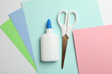 Photo of Glue, scissors and color paper on white background, flat lay