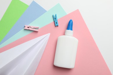 Photo of Glue, clips and color paper on white background, flat lay