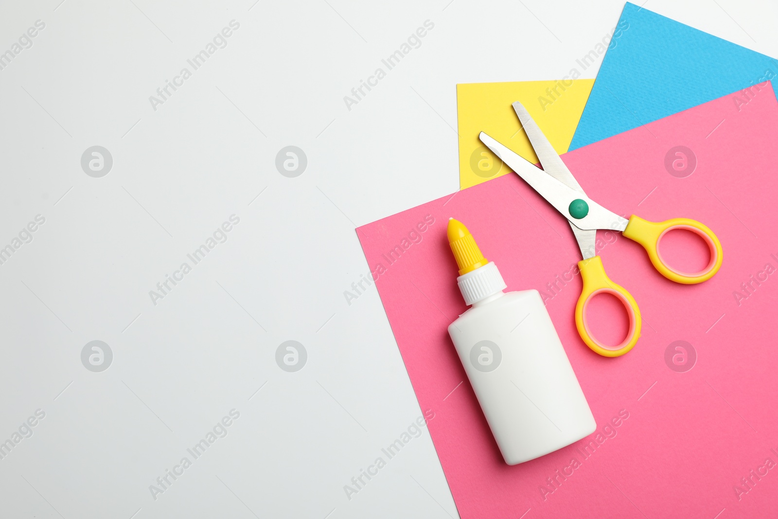 Photo of Glue, scissors and color paper on white background, flat lay. Space for text
