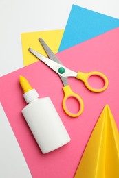 Photo of Glue, scissors, handmade plane and color paper on white background, flat lay