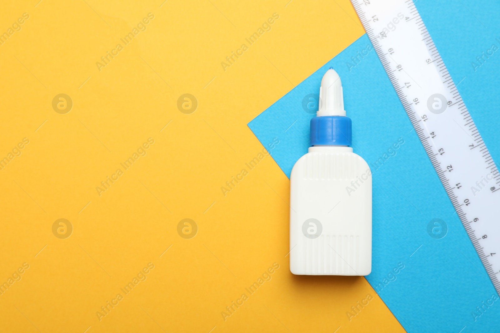 Photo of Glue, ruler and color paper on yellow background, flat lay. Space for text