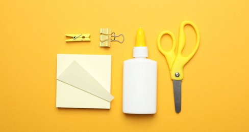 Photo of Glue and other stationery on yellow background, flat lay