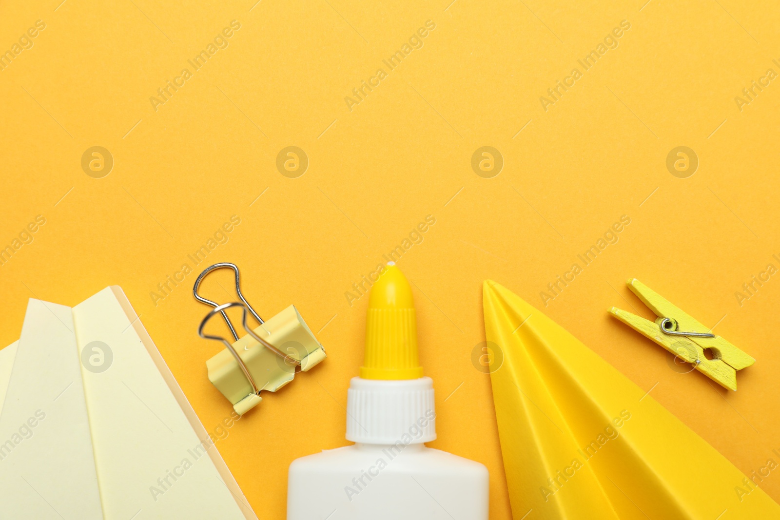 Photo of Glue and other stationery on yellow background, flat lay. Space for text