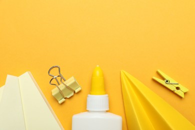 Photo of Glue and other stationery on yellow background, flat lay. Space for text