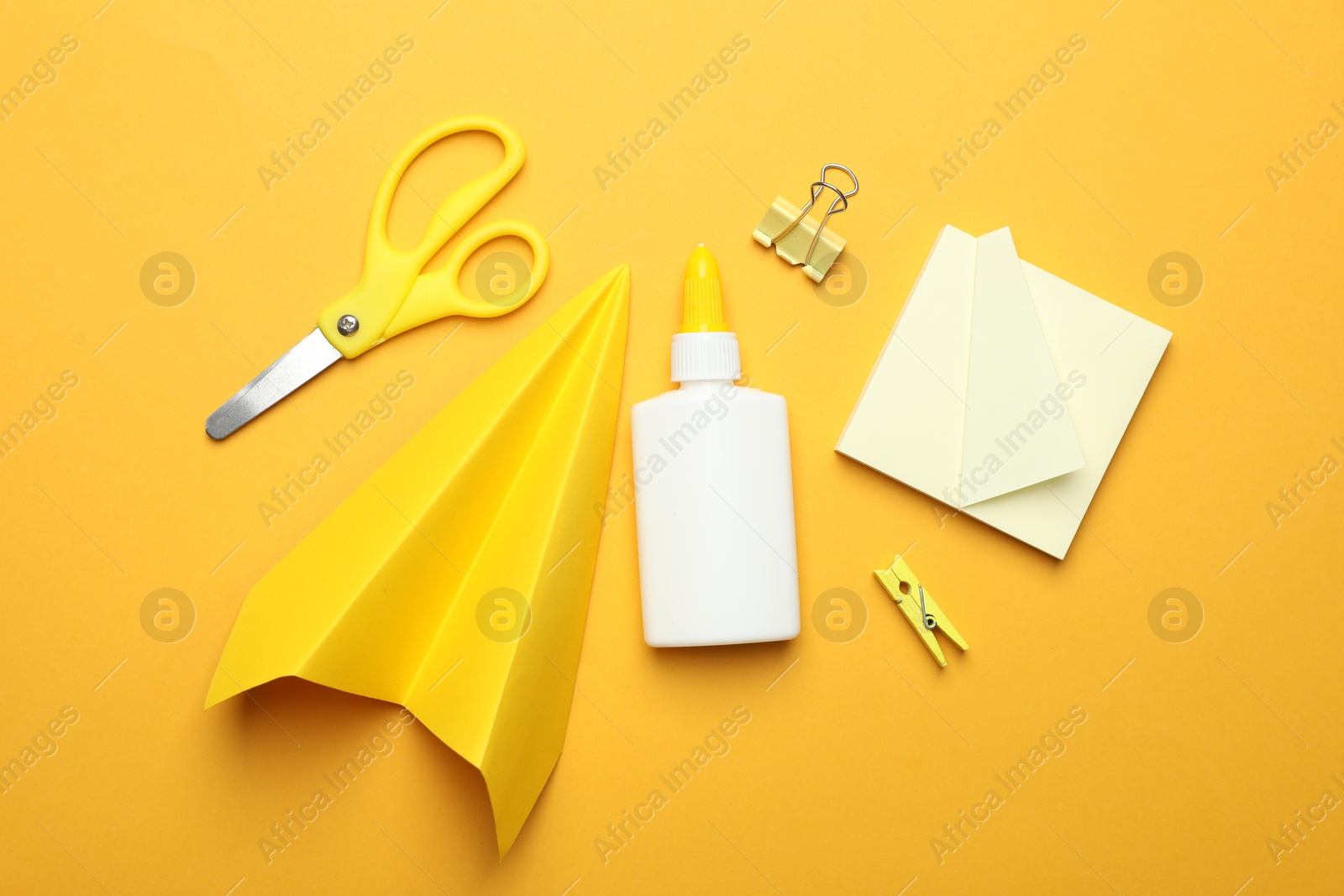 Photo of Glue and other stationery on yellow background, flat lay