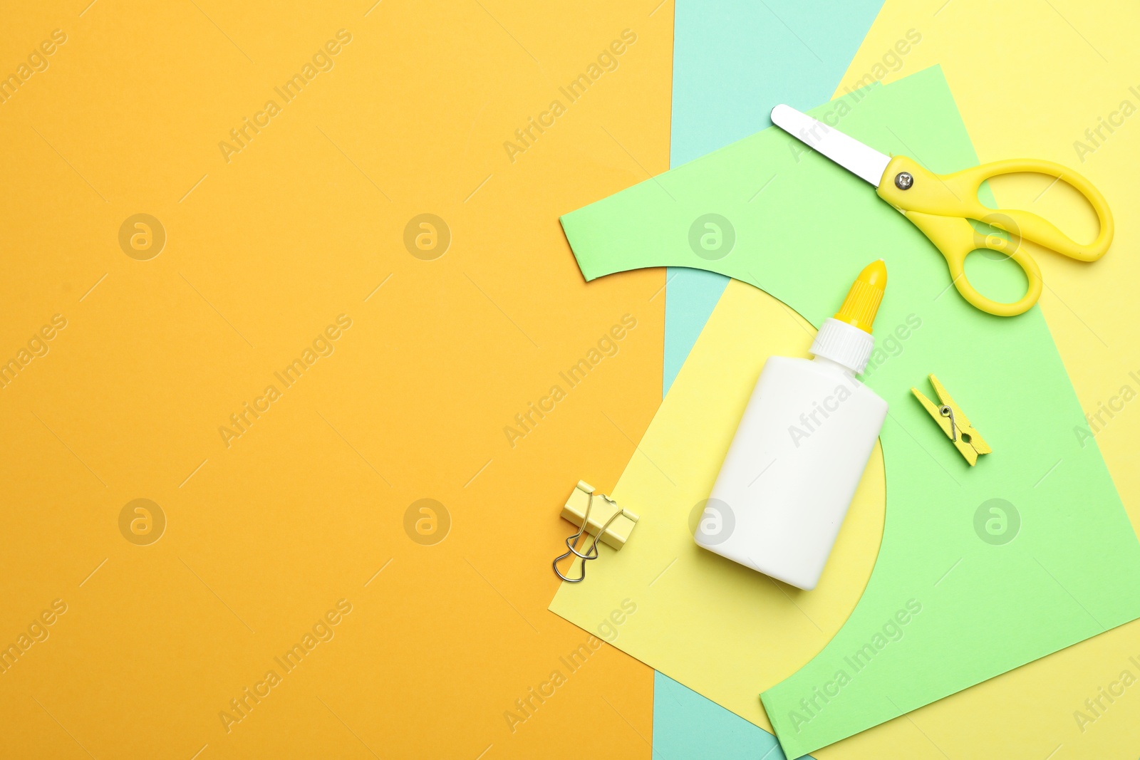 Photo of Glue and other stationery on yellow background, flat lay. Space for text