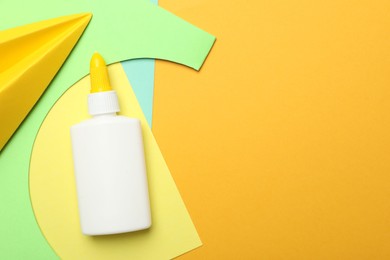 Photo of Glue, handmade plane and color paper on yellow background, flat lay. Space for text