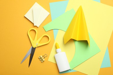 Photo of Glue and other stationery on yellow background, flat lay