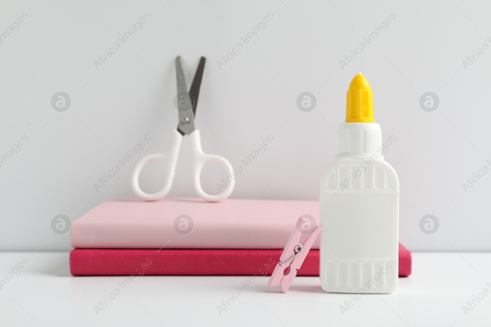 Photo of Glue, scissors, clip and notebooks on white table