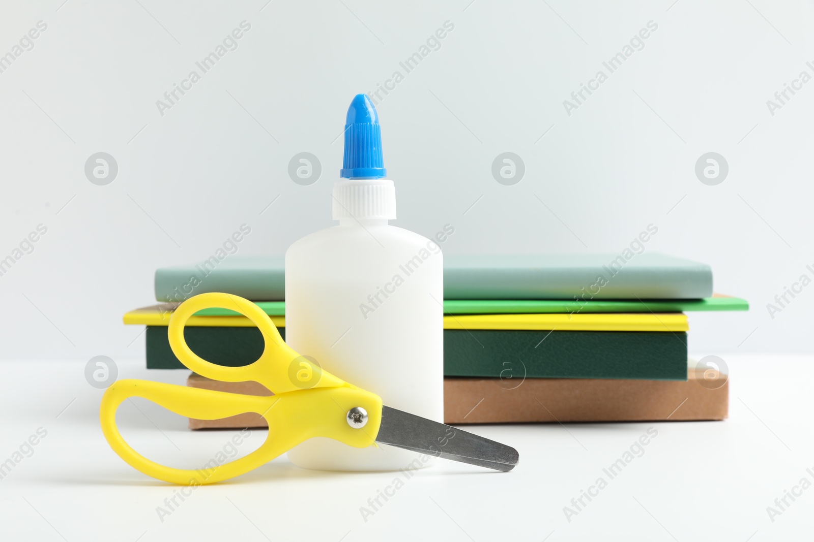 Photo of Glue, scissors and notebooks on white table