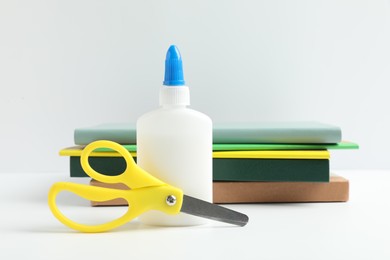Photo of Glue, scissors and notebooks on white table