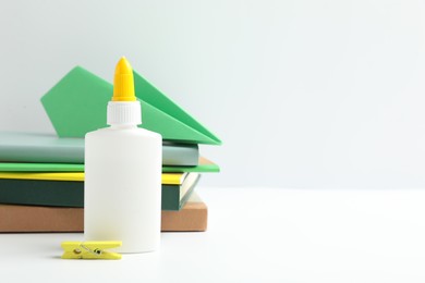 Photo of Glue, paper plane, clip and notebooks on white table. Space for text