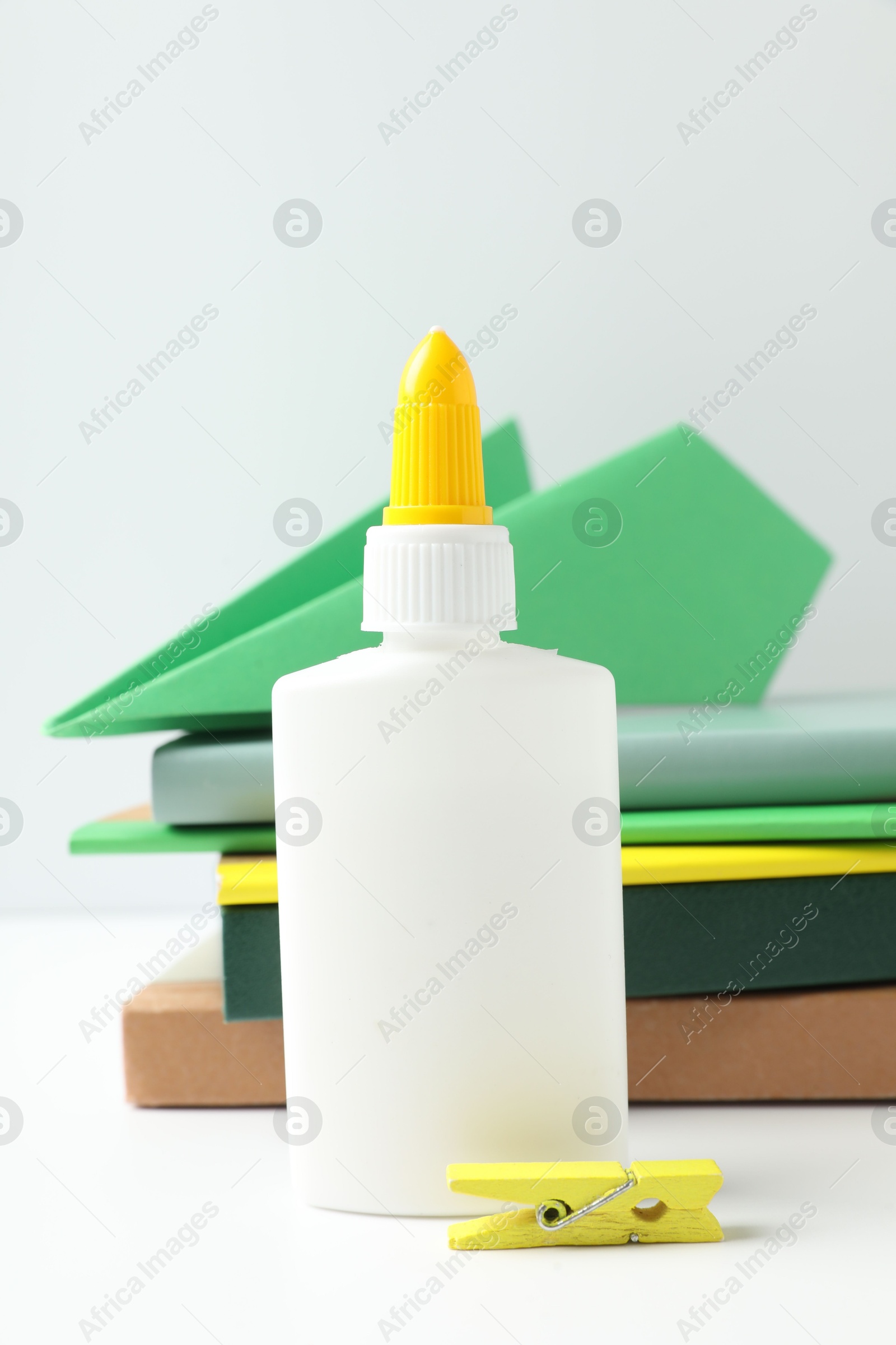 Photo of Glue, paper plane, clip and notebooks on white table
