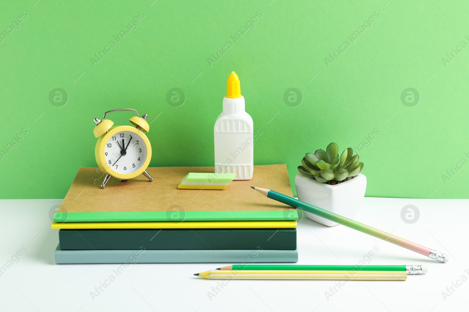 Photo of Glue and other stationery on white table against green background
