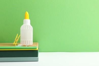 Photo of Glue and other stationery on white table against green background. Space for text
