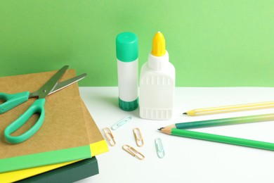 Photo of Glue and other stationery on white table against green background