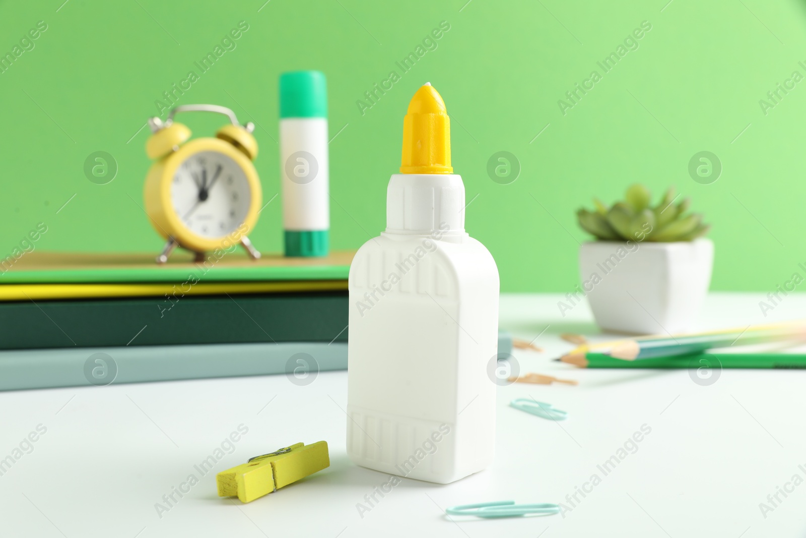 Photo of Glue and other stationery on white table against green background
