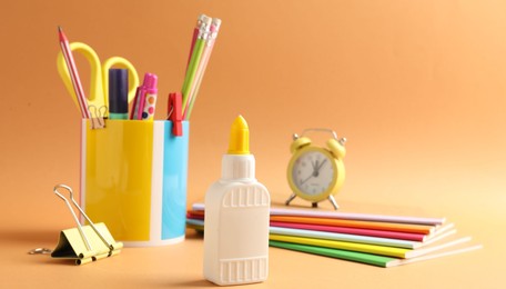 Photo of Glue and other stationery on pale orange background