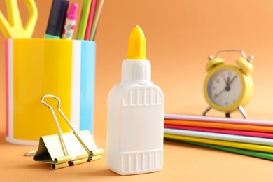 Photo of Glue and other stationery on pale orange background