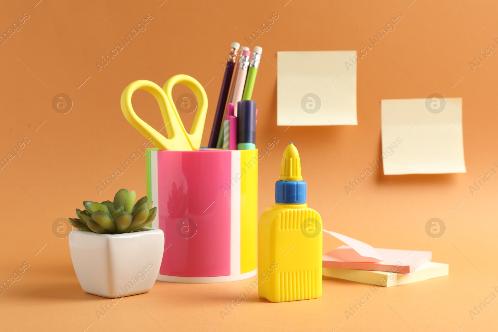 Photo of Glue and other stationery on pale orange background