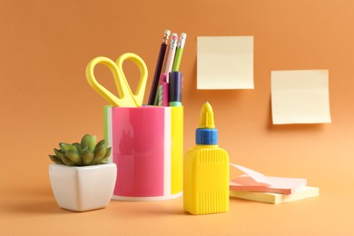 Photo of Glue and other stationery on pale orange background