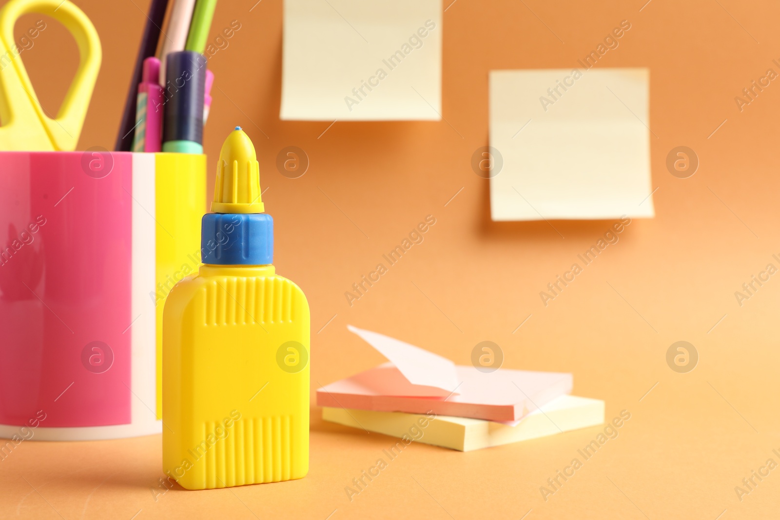 Photo of Glue and other stationery on pale orange background
