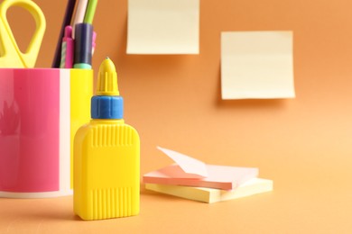 Photo of Glue and other stationery on pale orange background
