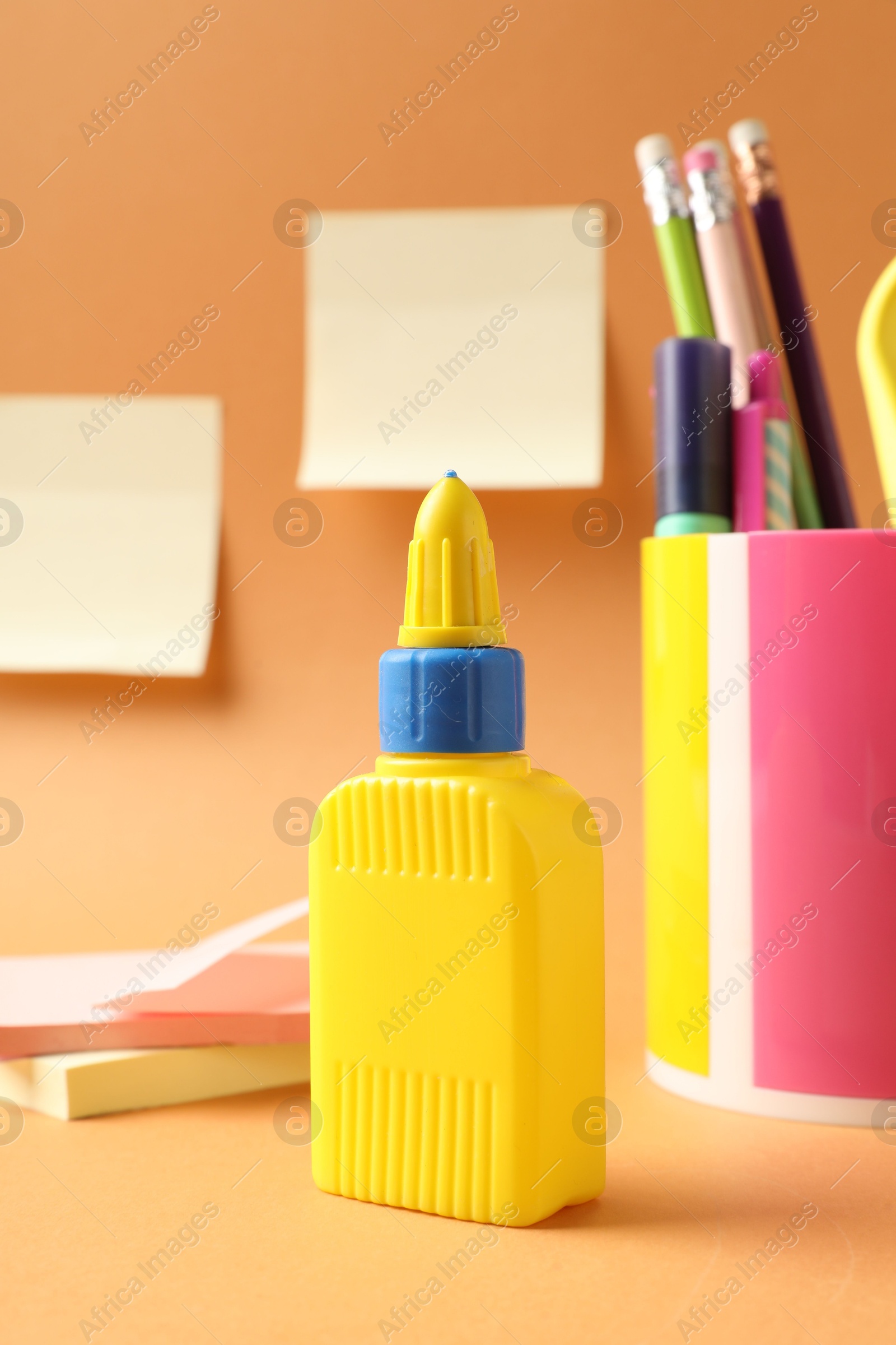 Photo of Glue and other stationery on pale orange background