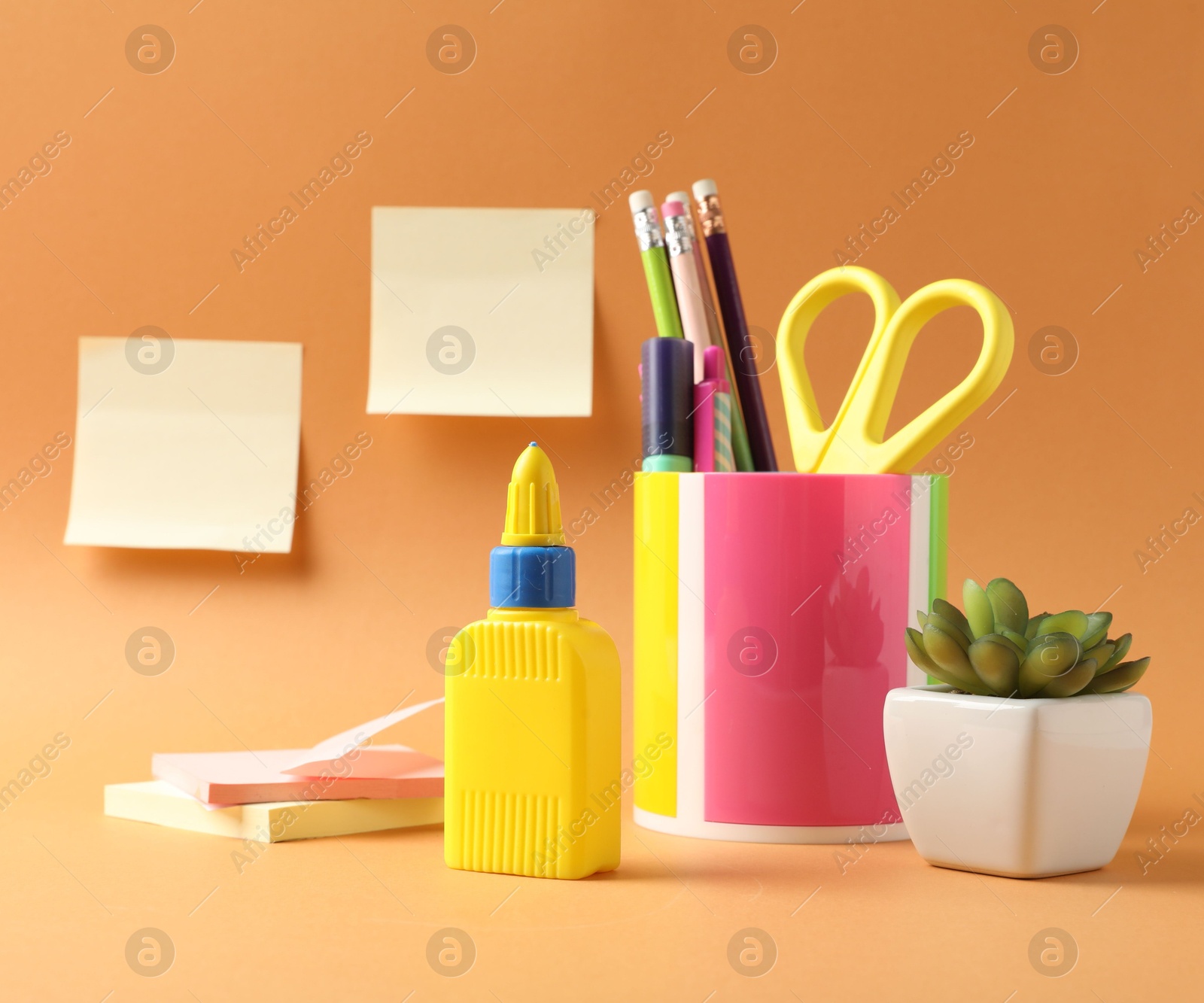 Photo of Glue and other stationery on pale orange background