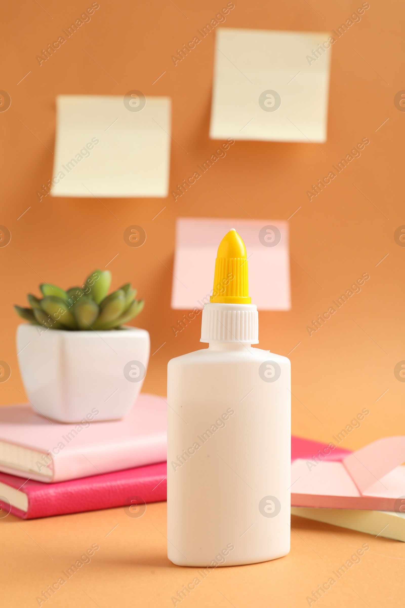 Photo of Glue and other stationery on pale orange background