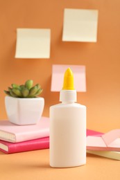 Photo of Glue and other stationery on pale orange background