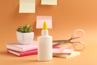 Photo of Glue and other stationery on pale orange background
