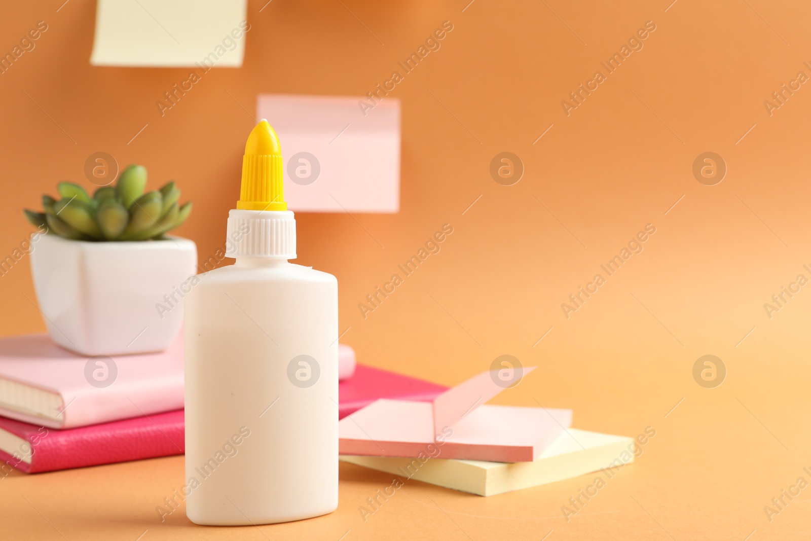 Photo of Glue and other stationery on pale orange background. Space for text