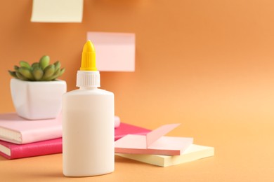 Photo of Glue and other stationery on pale orange background. Space for text