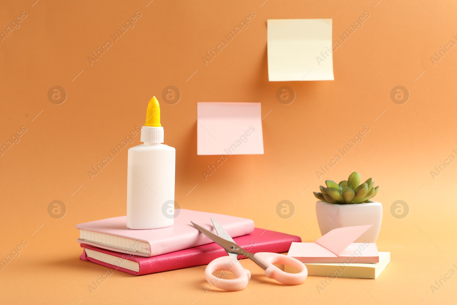Photo of Glue and other stationery on pale orange background