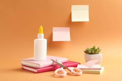 Photo of Glue and other stationery on pale orange background