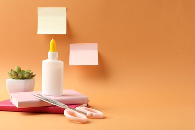 Photo of Glue and other stationery on pale orange background. Space for text