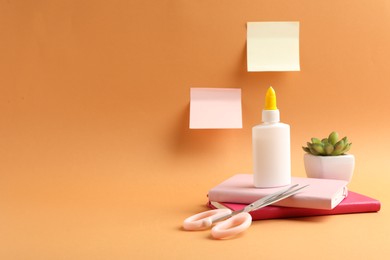 Photo of Glue and other stationery on pale orange background. Space for text