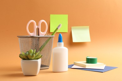 Photo of Glue and other stationery on pale orange background
