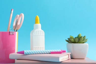 Photo of Glue and other stationery on light blue background, closeup