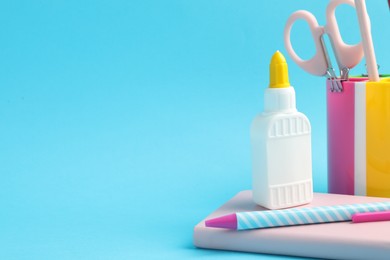 Photo of Glue and other stationery on light blue background. Space for text