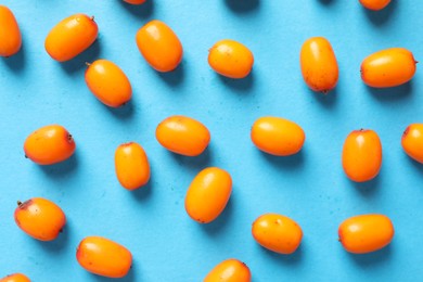 Photo of Ripe sea buckthorn berries on light blue background, flat lay