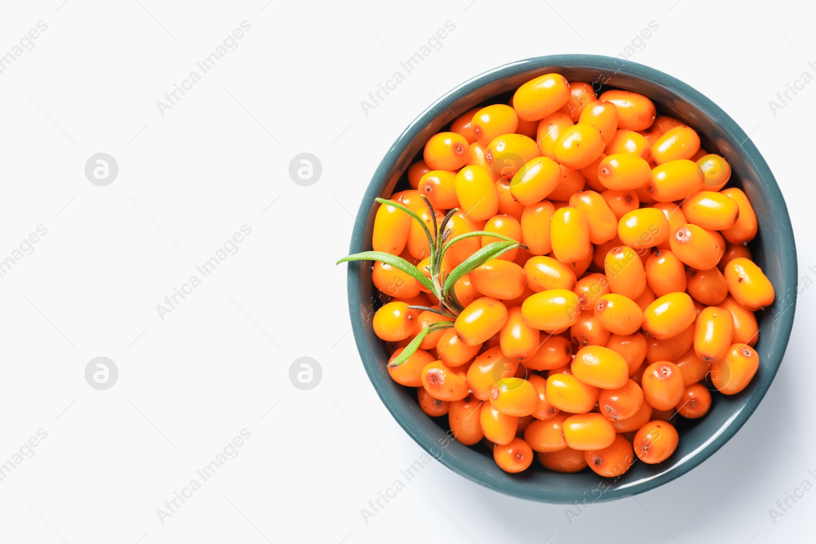 Photo of Ripe sea buckthorn berries and leaves in bowl on white background, top view. Space for text