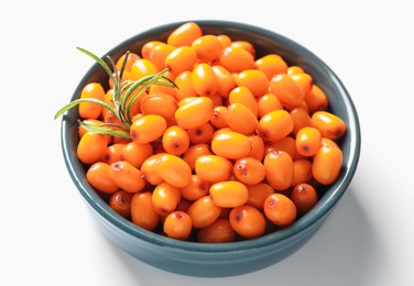 Photo of Ripe sea buckthorn berries and leaves in bowl on white background, closeup